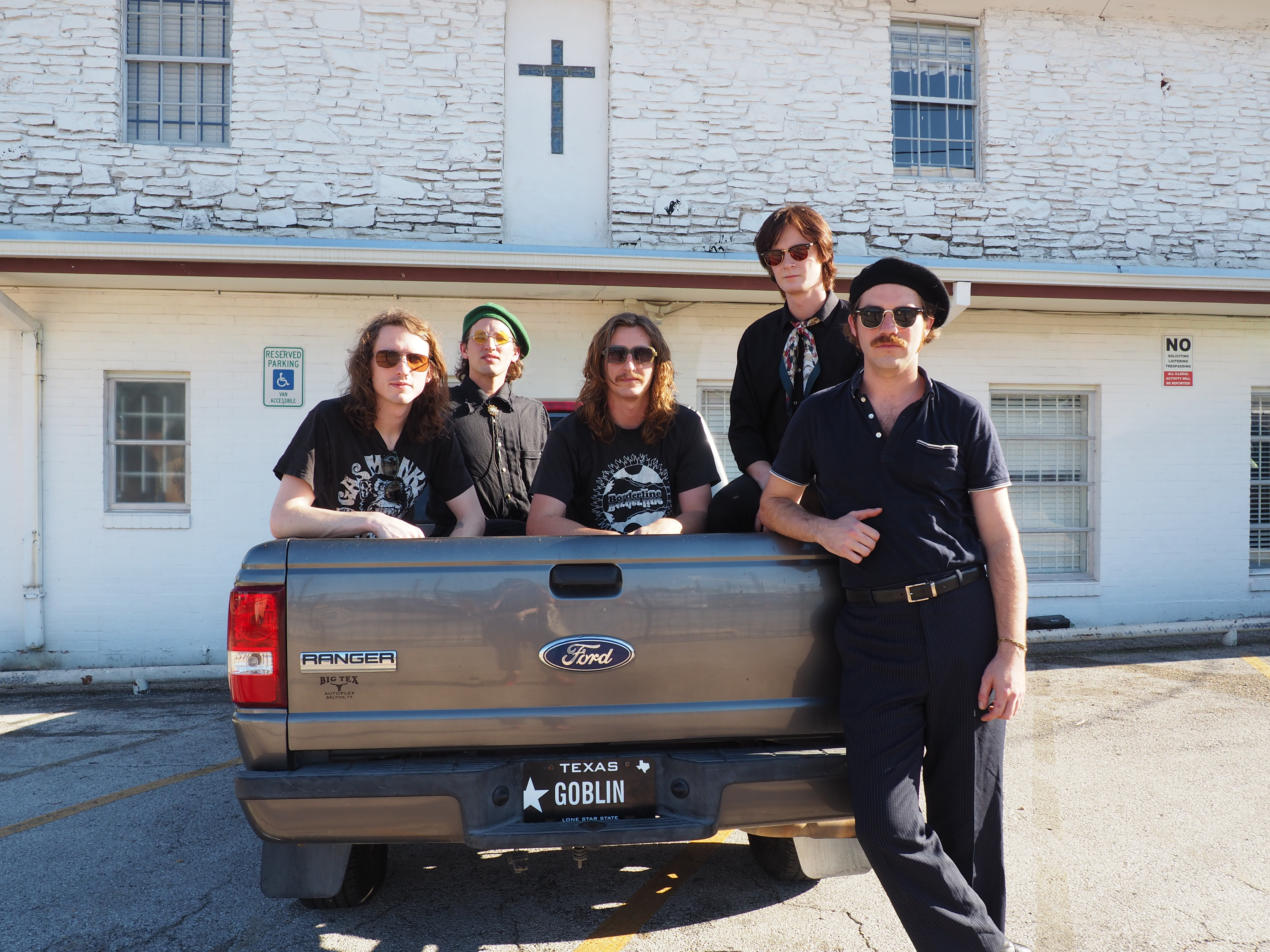 Five people sitting in the back of a pickup truck dressed in black