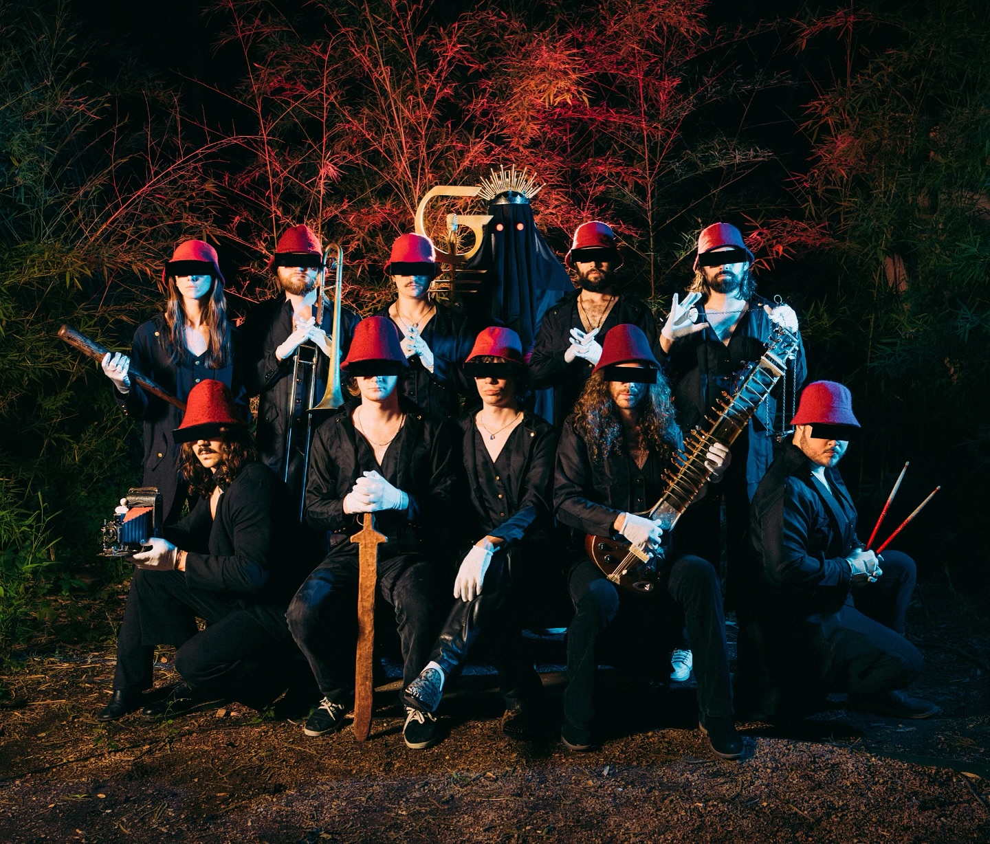 Five people sitting in the back of a pickup truck dressed in black
